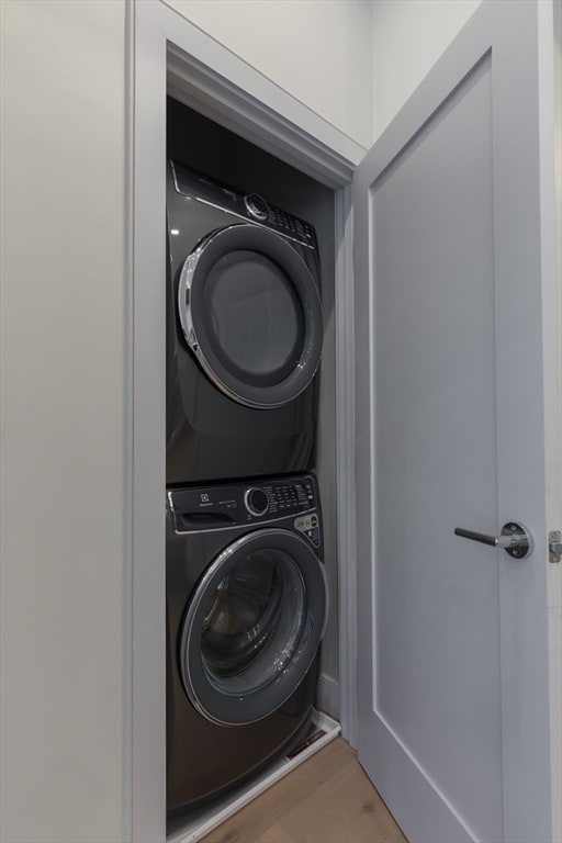 laundry area with hardwood / wood-style floors and stacked washer and dryer