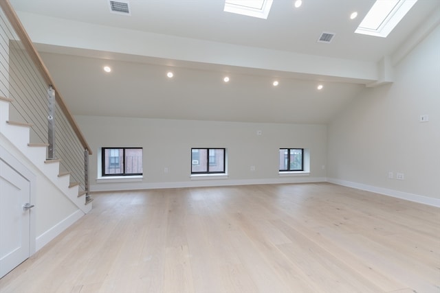 unfurnished living room with light hardwood / wood-style flooring, high vaulted ceiling, and a skylight