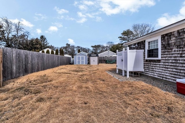 view of yard with an outbuilding, a storage unit, and a fenced backyard