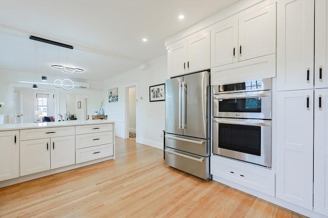 kitchen featuring appliances with stainless steel finishes, light wood-style flooring, recessed lighting, white cabinets, and a chandelier