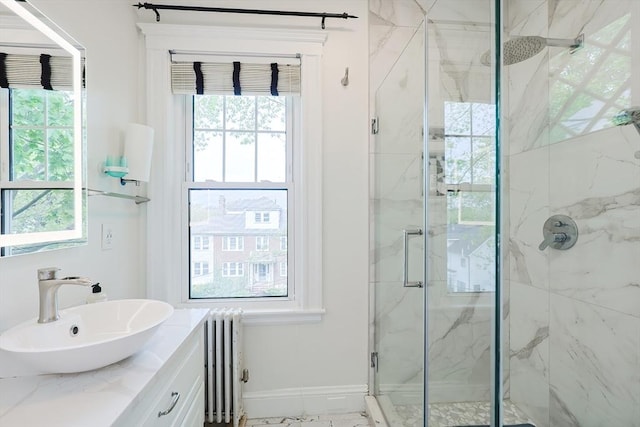 full bath with radiator heating unit, a marble finish shower, healthy amount of natural light, and vanity