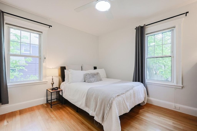 bedroom with light wood-style floors, baseboards, and a ceiling fan