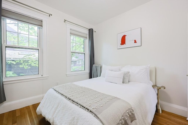 bedroom with wood finished floors, baseboards, and radiator heating unit