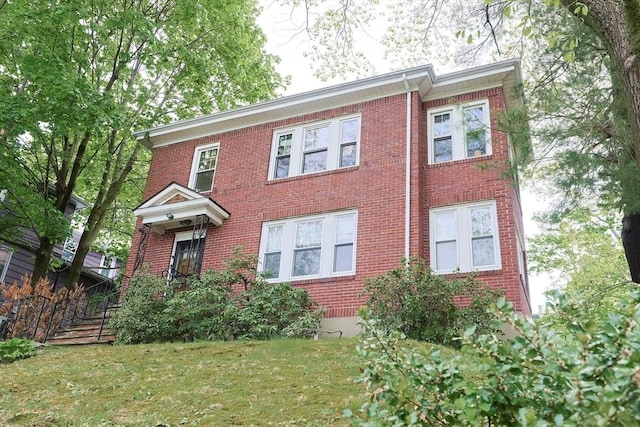 colonial-style house featuring brick siding and a front lawn