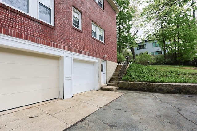 view of home's exterior with brick siding, driveway, stairs, and an attached garage