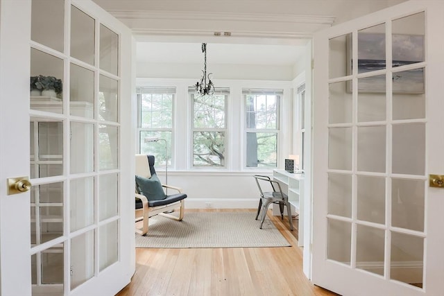 sitting room featuring wood finished floors, a chandelier, a desk, and baseboards