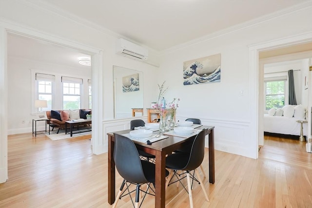 dining room featuring a wall mounted AC, light wood-style flooring, ornamental molding, a wainscoted wall, and a decorative wall