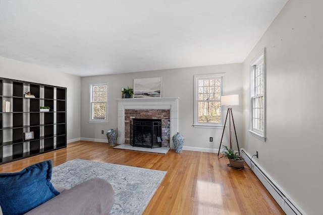 living area featuring wood finished floors, a fireplace, baseboards, and a baseboard radiator