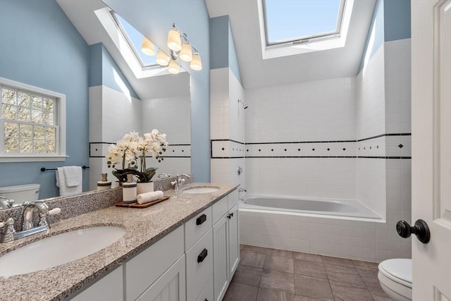 bathroom with tile patterned floors, vaulted ceiling with skylight, toilet, and a sink