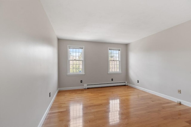 empty room featuring baseboards, light wood-type flooring, and a baseboard radiator