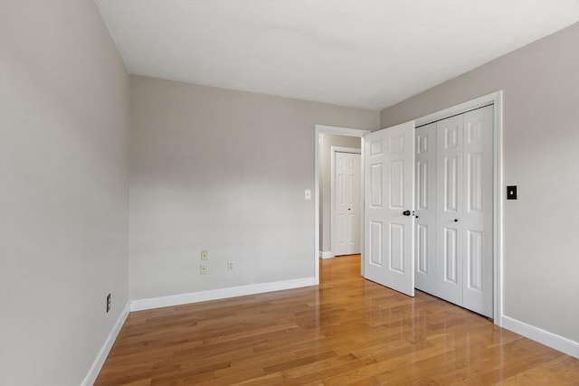 unfurnished bedroom with a closet, baseboards, and light wood finished floors