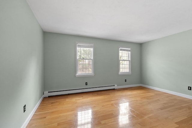 empty room featuring light wood finished floors, baseboards, and a baseboard radiator