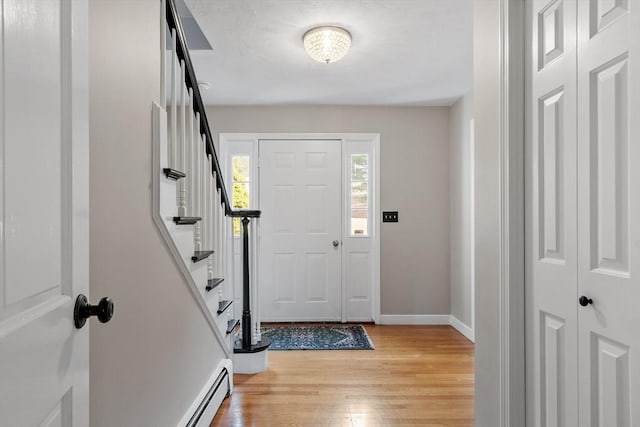 entrance foyer with light wood-type flooring, baseboards, stairs, and a baseboard radiator