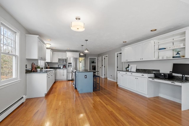 kitchen with a baseboard heating unit, dark countertops, built in study area, and stainless steel appliances