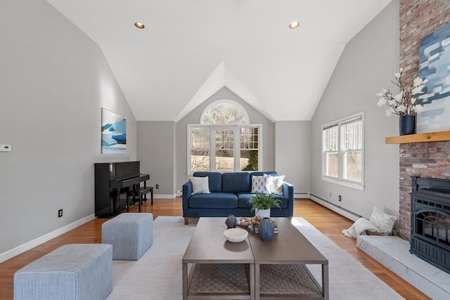 living room with a wood stove, wood finished floors, baseboards, and a baseboard radiator