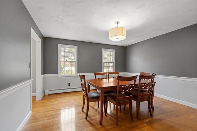 dining area featuring baseboards, light wood-style floors, and a baseboard radiator