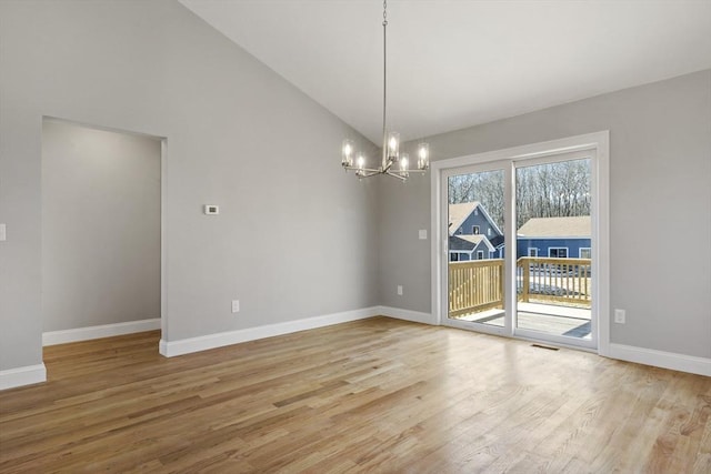 unfurnished dining area with an inviting chandelier, wood-type flooring, and high vaulted ceiling