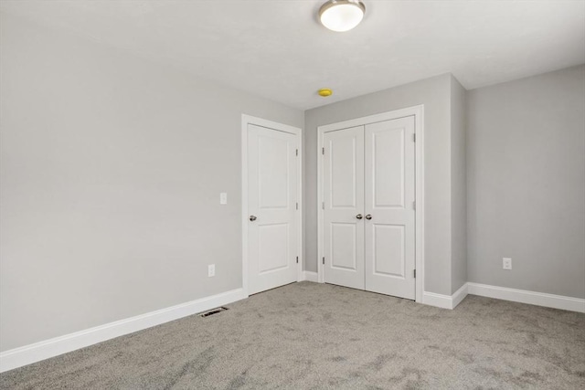 unfurnished bedroom with light colored carpet and a closet