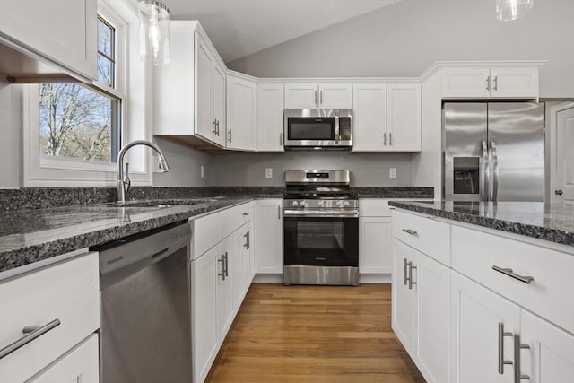 kitchen featuring vaulted ceiling, hardwood / wood-style floors, sink, white cabinets, and stainless steel appliances