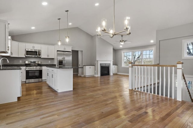 kitchen with white cabinetry, appliances with stainless steel finishes, a kitchen island, pendant lighting, and a healthy amount of sunlight