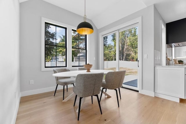 dining room with vaulted ceiling and light hardwood / wood-style floors