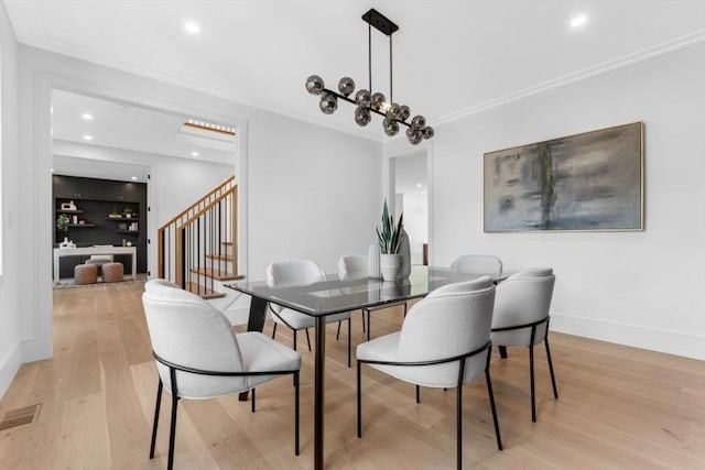 dining space with ornamental molding and light hardwood / wood-style floors