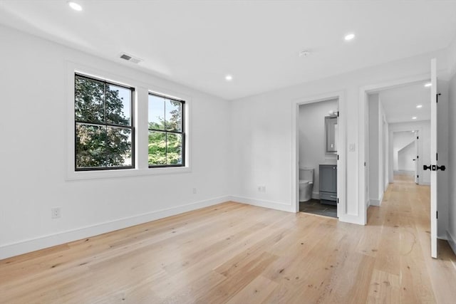 unfurnished bedroom with ensuite bathroom and light wood-type flooring