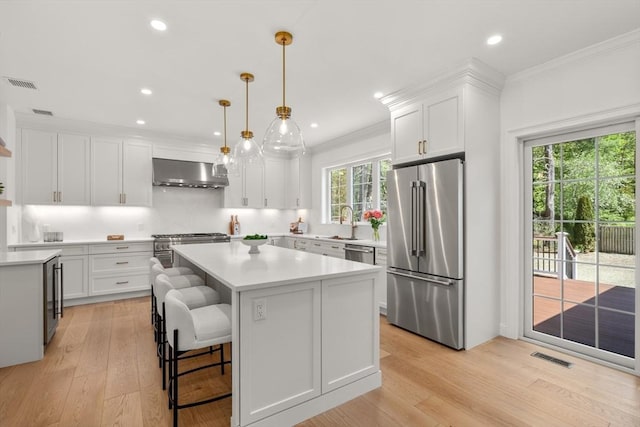1 Cole Rd, Wayland, MA 01778 - kitchen featuring stainless steel appliances, wall chimney exhaust hood, a sink, light countertops, and white cabinetry