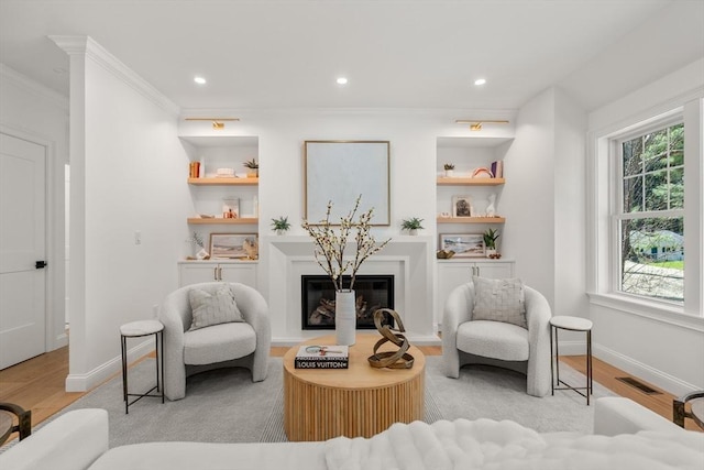 1 Cole Rd, Wayland, MA 01778 - sitting room with light wood finished floors, crown molding, baseboards, built in shelves, and a glass covered fireplace