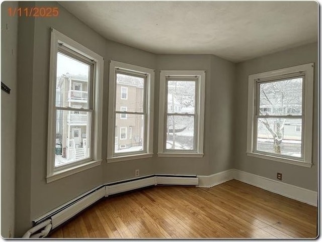 empty room featuring baseboard heating and light hardwood / wood-style floors