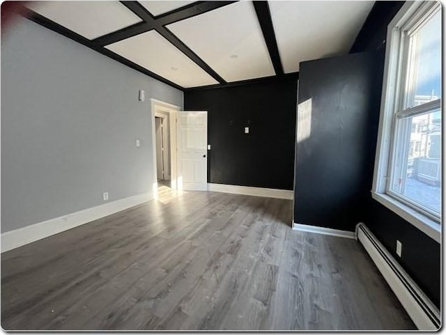 spare room with baseboard heating, coffered ceiling, dark wood-type flooring, and a wealth of natural light