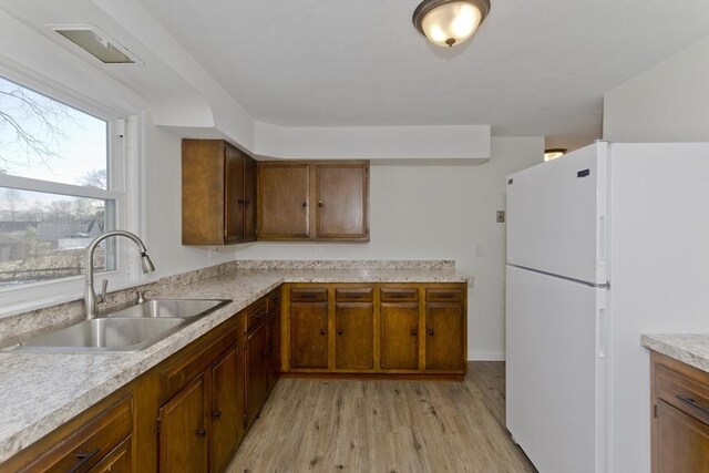 kitchen with sink, light hardwood / wood-style flooring, and white fridge