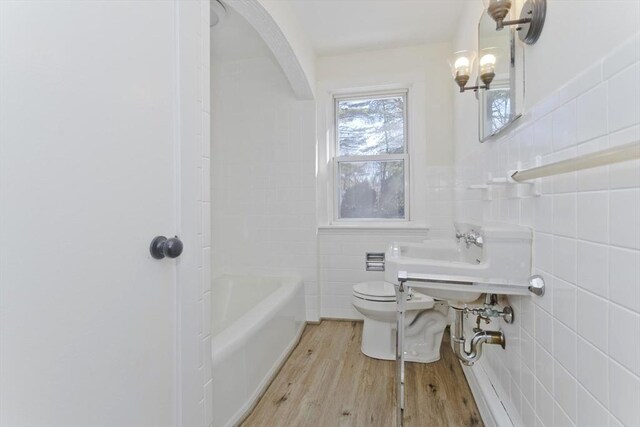 bathroom with tile walls, hardwood / wood-style floors, and toilet