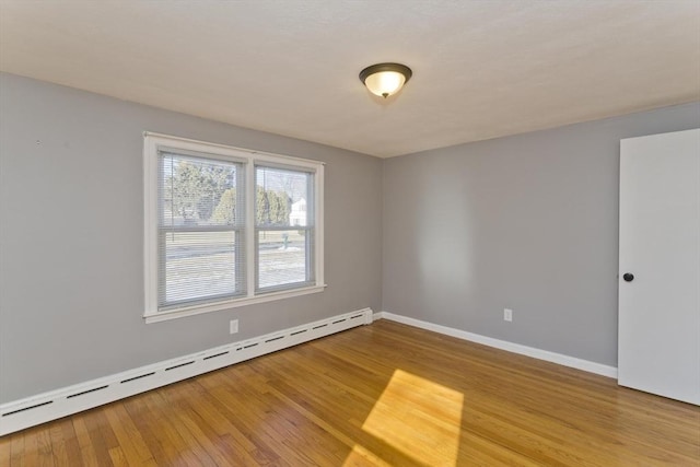 spare room with a baseboard radiator and hardwood / wood-style floors