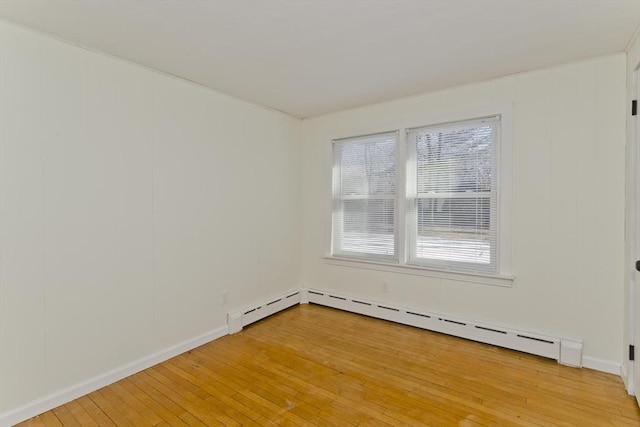 spare room featuring a baseboard heating unit and wood-type flooring