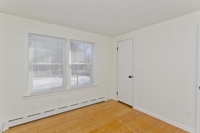 unfurnished room with baseboard heating and wood-type flooring