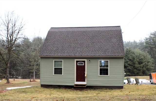 view of front of home featuring entry steps, a front lawn, and a shingled roof