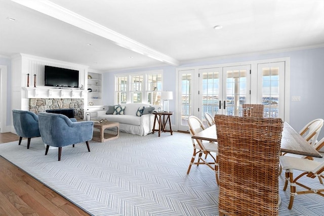 sunroom / solarium with a stone fireplace, french doors, and beamed ceiling