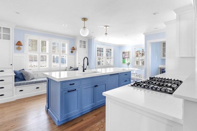 kitchen featuring a sink, light countertops, ornamental molding, blue cabinetry, and stainless steel gas stovetop