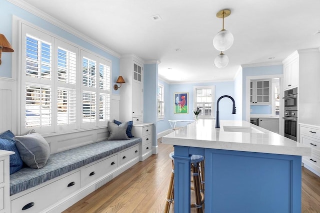 kitchen featuring light countertops, light wood finished floors, and a sink