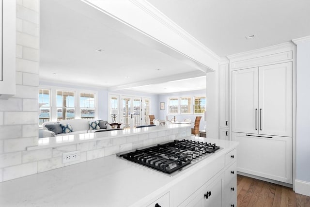 kitchen featuring stainless steel gas cooktop, wood finished floors, white cabinetry, open floor plan, and light countertops