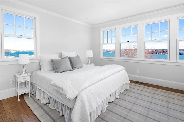 bedroom with baseboards, wood finished floors, visible vents, and crown molding