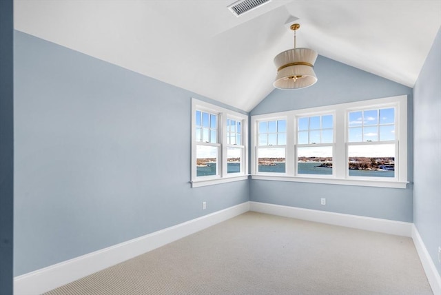 spare room featuring light colored carpet, lofted ceiling, a healthy amount of sunlight, and visible vents