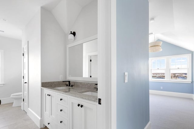 full bathroom featuring lofted ceiling, double vanity, a sink, and toilet