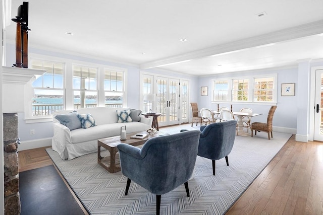 living room featuring light wood-style floors, crown molding, baseboards, and a wealth of natural light