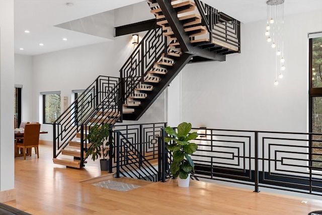 stairs featuring wood finished floors, recessed lighting, a high ceiling, and baseboards