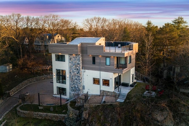 back of property at dusk with a balcony and stucco siding