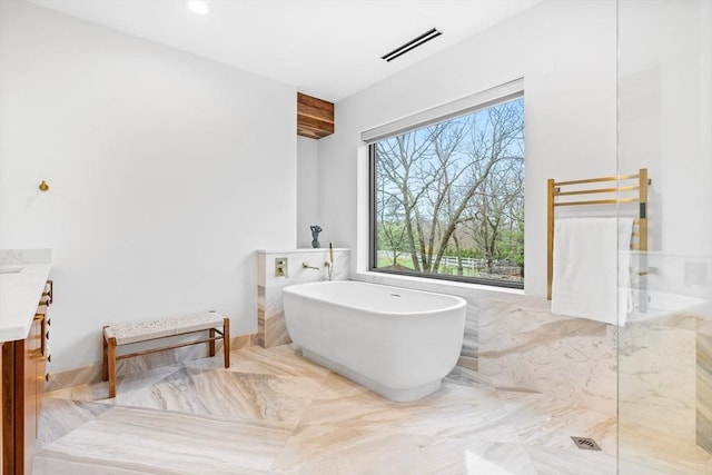 full bathroom with a freestanding bath, vanity, tile walls, marble finish floors, and a shower