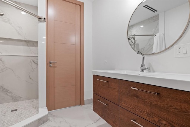 bathroom with a marble finish shower, marble tiled floors, and vanity