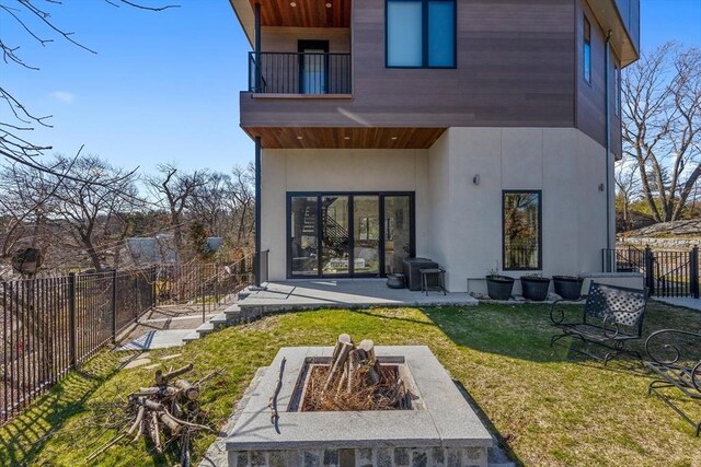 back of house featuring a fire pit, a balcony, a patio area, and stucco siding